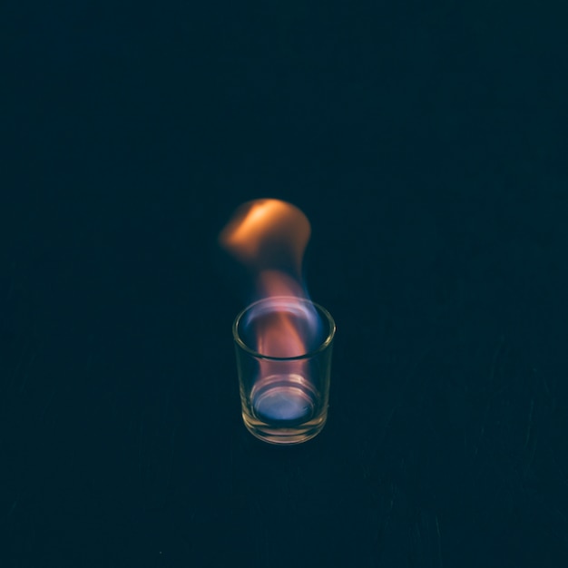 Бесплатное фото Сжигание текилы выстрел из стекла на темном фоне