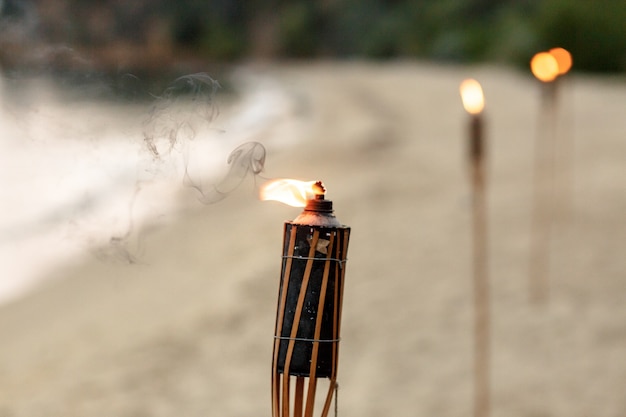 Free photo burning torches stand in row on sand beach