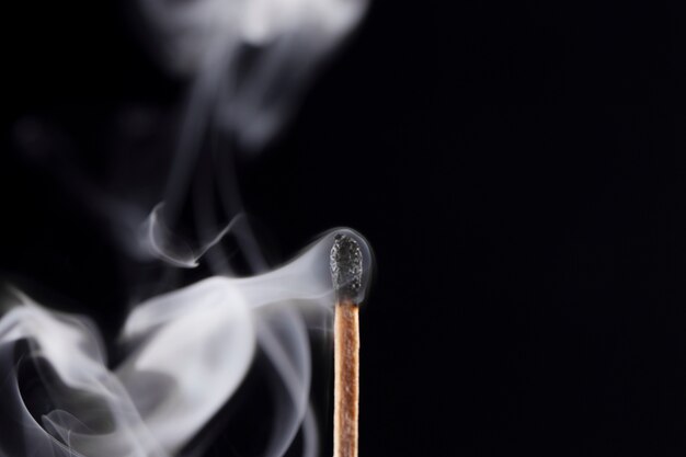 burnt match with smoke and dark background