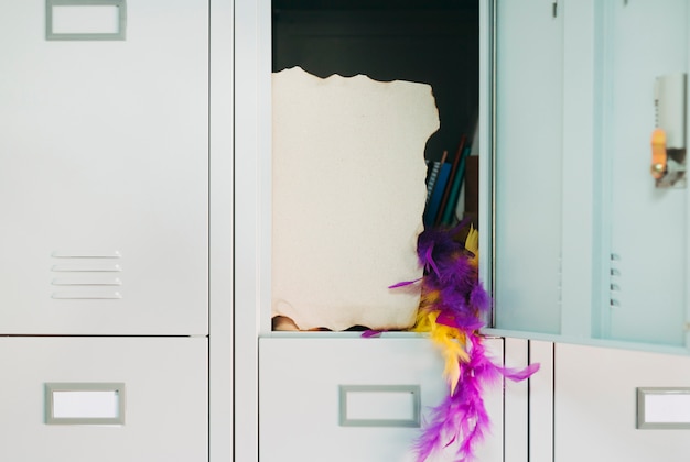 Burnt page with yellow and purple feather boa hanging from open safety locker