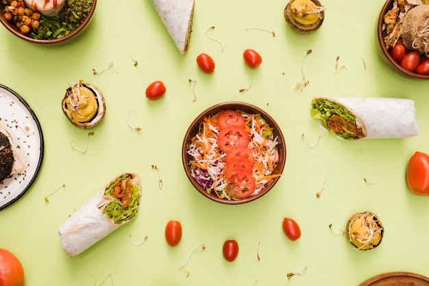 Burrito wrap; cherry tomatoes and salad bowl on mint green backdrop