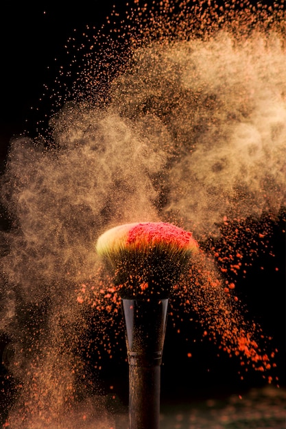 Burst of powder and makeup brush on dark background