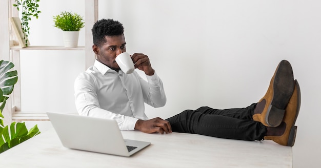 Деловой афро-американский мужчина пьет кофе в офисе