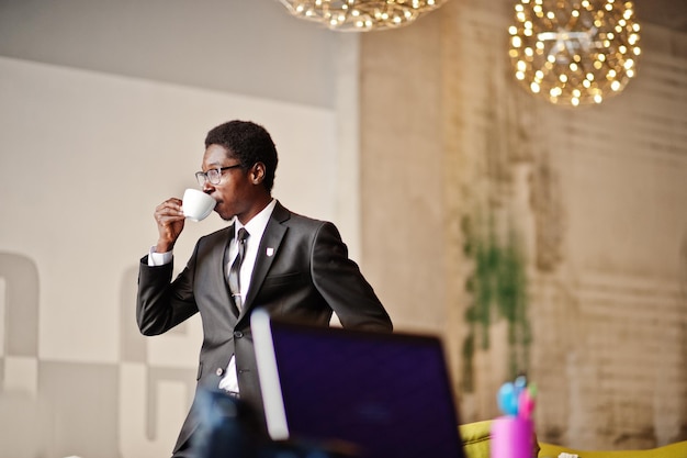 無料写真 ビジネスアフリカ系アメリカ人の男性は、仕事の日の前に朝のコーヒーを飲むオフィスで黒いスーツと眼鏡を着用します