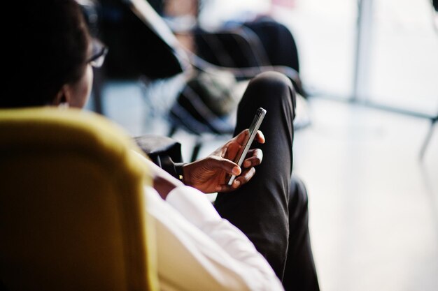 비즈니스 아프리카계 미국인 남자는 의자에 앉아서 휴대 전화를 들고 사무실에서 흰색 셔츠 넥타이와 안경을 착용