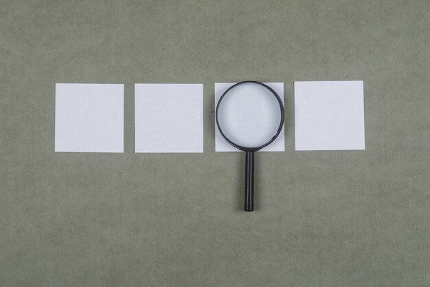 Business analysis concept with sticky notes, magnifying glass on grey surface flat lay.