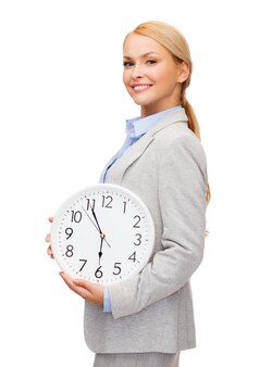 Концепция бизнеса и времени - привлекательная деловая женщина с настенными часами