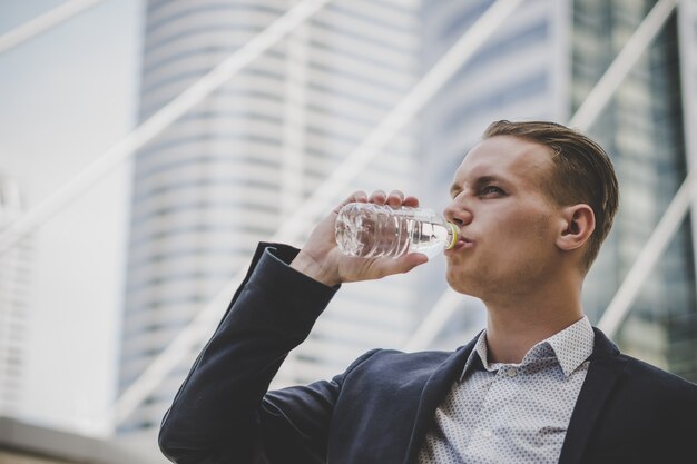 Business businessman take a rest drinking water in front of business center.