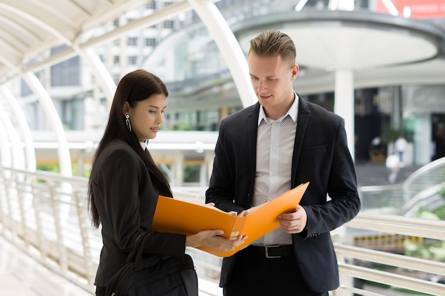 Business colleague talking and viewing documents outdoor