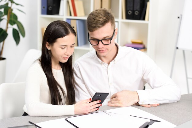 Business colleagues looking at cellphone at workplace in the office