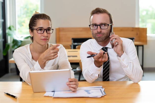 Foto gratuita colleghi di lavoro che punta a qualcosa e utilizzando i dispositivi.