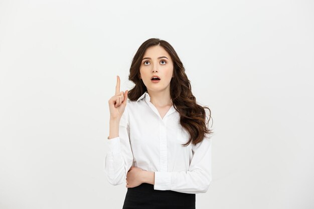 Бизнес-концепция привлекательная молодая кавказская девушка открывает рот и указывает указательным пальцем на