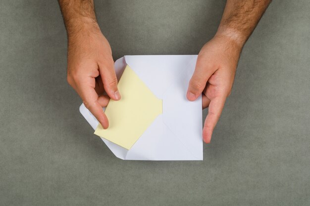 Business concept on grey surface flat lay. man taking letter out of envelope.