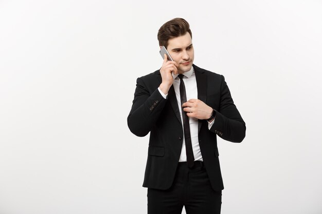 Business Concept: Handsome businessman in suit and speaking on the phone over isolated grey background.