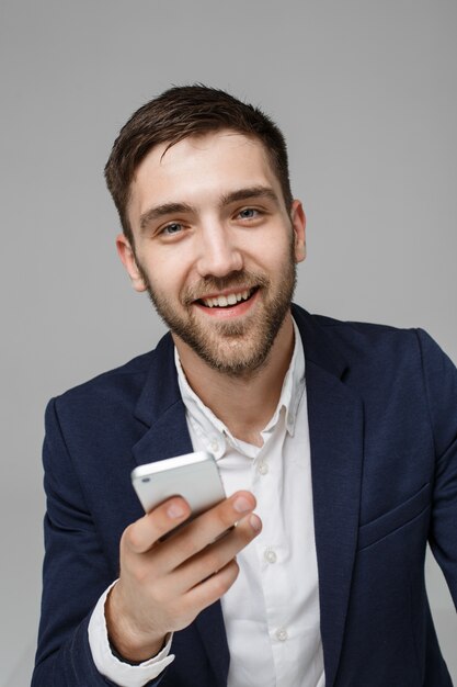 Бизнес-концепция - портрет Красивый деловой человек, играя телефон с улыбающимся уверенным лицом. Белый фон. Копирование пространства.