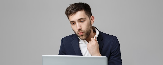 Бизнес-концепция Портрет красивый напряженный деловой человек в шоковом костюме, глядя на работу в ноутбуке на белом фоне