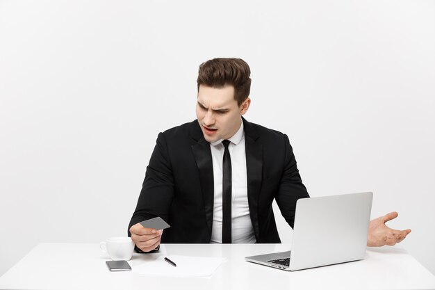 Business concept portrait of young businessman using laptop computer and mobile phone holding debit ...