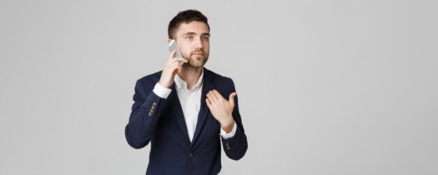 Business Concept Portrait young handsome angry business man in suit talking on phone looking at camera White background