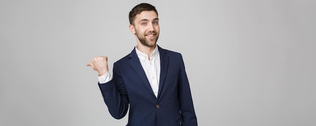 Business Concept portrait young successful businessman pointing finger over dark background Copy space