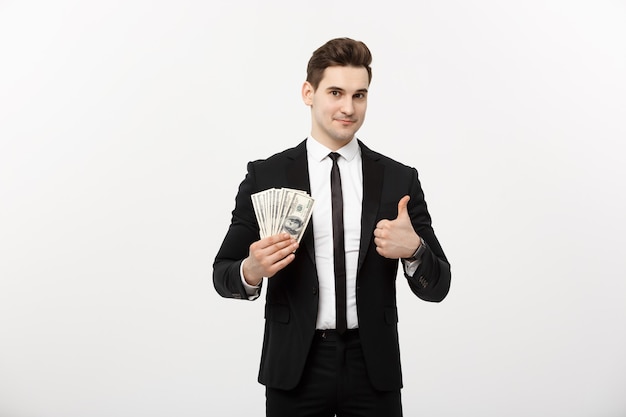 Business concept - successful businessman holding dollar bills and showing thumb up isolated over white background.