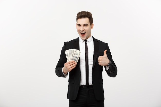 Business concept - successful businessman holding dollar bills and showing thumb up isolated over white background.