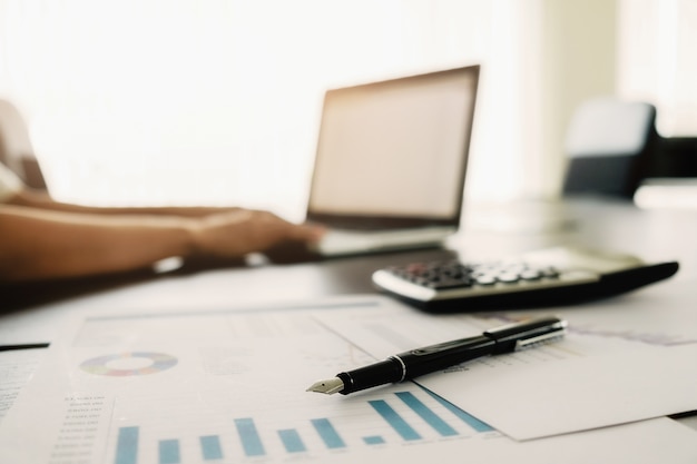 Business concept with copy space. Office desk table with pen focus and analysis chart, computer, notebook, cup of coffee on desk.Vintage tone Retro filter, selective focus.