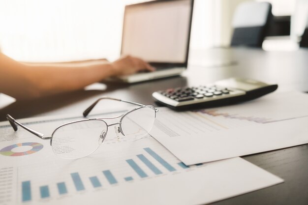 Business concept with copy space. Office desk table with pen focus and analysis chart, computer, notebook, cup of coffee on desk.Vintage tone Retro filter, selective focus.