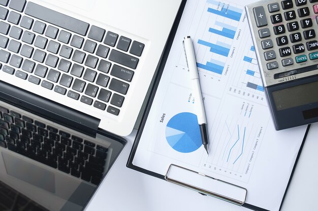 Business concept with copy space. Office desk table with pen focus and analysis chart, computer, notebook, cup of coffee on desk.Vintage tone Retro filter, selective focus.