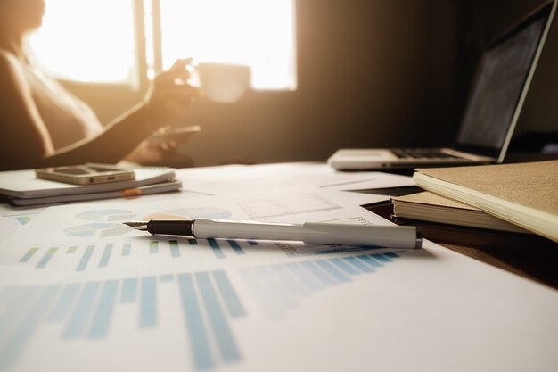 Business concept with copy space. Office desk table with pen focus and analysis chart, computer, notebook, cup of coffee on desk.Vintage tone Retro filter, selective focus.