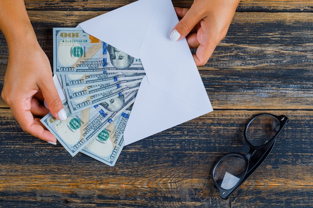 Business concept with glasses and envelope with money on wooden surface