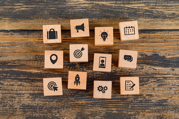 Business concept with icons on wooden cubes on wooden table flat lay.
