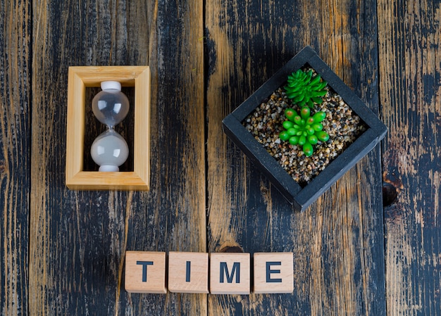 Free photo business concept with time word on wooden cubes, hourglass and plant