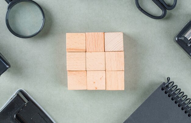 Business concept with wooden blocks, black notebook, magnifying glass top view.