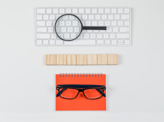 Бесплатное фото Бизнес-концепция с деревянными блоками, очки, увеличительное стекло на клавиатуре на белом фоне плоской планировки.
