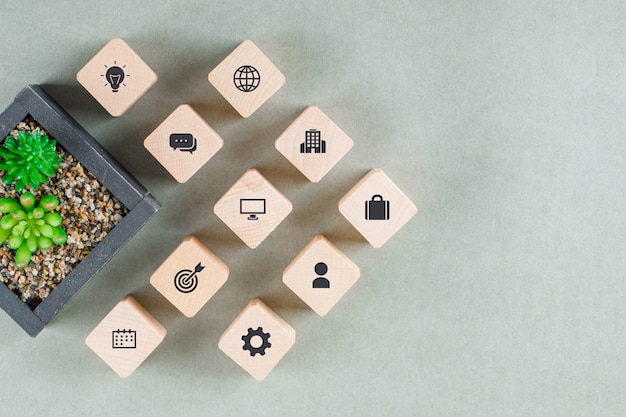 Business concept with wooden blocks with icons, green plant. 
