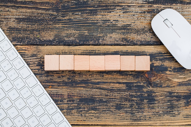 Business concept with wooden cubes, computer mouse and keyboard on wooden background flat lay.