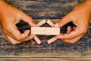 Free photo business concept on wooden background flat lay. hand merging wooden blocks.