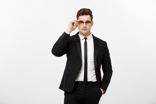 ビジネスコンセプト：白い背景で隔離のポケットに手を持って眼鏡をかけて若いハンサムなビジネスマン。