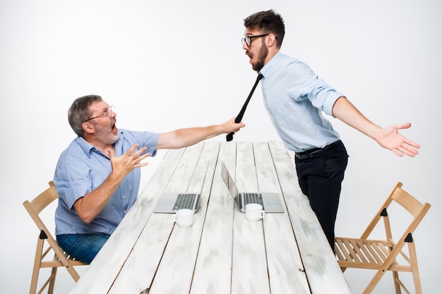 Бесплатное фото Деловой конфликт. двое мужчин выражают негатив, в то время как один мужчина хватает галстук ее соперницы