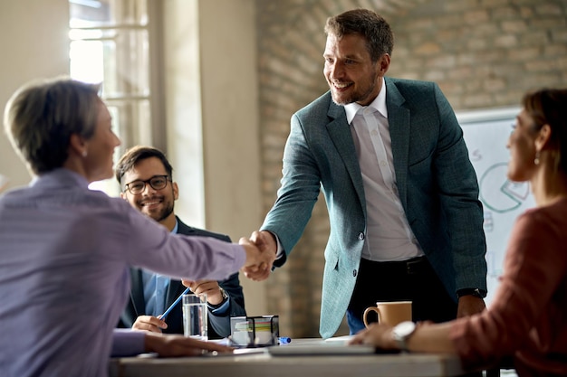 オフィスでの会議中に握手するビジネス同僚焦点はビジネスマンにあります
