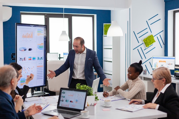 Business executive owner criticizing multiethnic workers for corporate problem failure shouting screaming in conference room