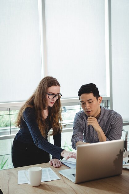 Business executives discussing over laptop