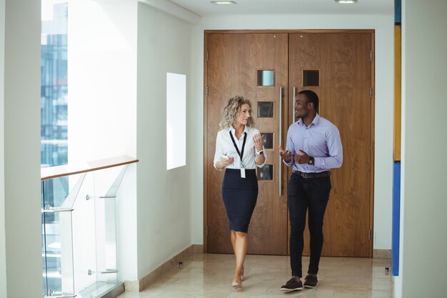 Business executives having a discussion while walking in corridor