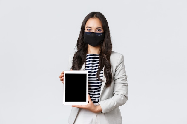 비즈니스, 금융 및 고용, covid-19는 바이러스 및 사회적 거리 개념을 예방합니다. 디지털 태블릿 화면에서 클라이언트에 대한 거래를 보여주는 자신감 있는 여성 부동산 중개인, 얼굴 마스크 착용