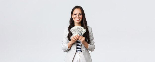 Business finance and employment entrepreneur and money concept Successful young asian office manager businesswoman showing earned cash smiling satisfied as holding dollars