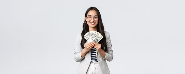 비즈니스 금융 및 고용 기업가 및 돈 개념 성공적인 젊은 아시아 사무실 관리자 사업가가 달러를 들고 만족스럽게 웃는 모습을 보여줍니다.
