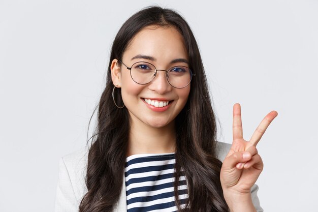 Business, finance and employment, female successful entrepreneurs concept. Close-up of friendly outgoing asian office employee showing peace sign and smiling optimistic, have all under control