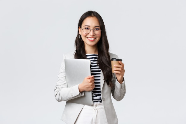 Business, finance and employment, female successful entrepreneurs concept. Confident good-looking businesswoman in glasses and suit drinking takeaway coffee and carry work laptop