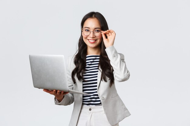 비즈니스, 금융 및 고용, 여성의 성공적인 기업가 개념. 웃고 있는 자신감 넘치는 아시아 여성 사업가, 흰색 정장을 입은 회사원, 노트북을 사용하는 안경