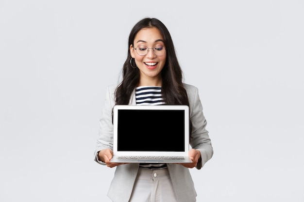 Business, finance and employment, female successful entrepreneurs concept. Enthusiastic businesswoman in suit and glasses showing presentation, demonstrate her project on laptop screen